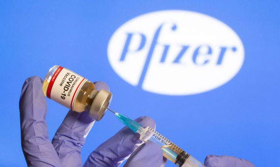 Mulher segura frasco rotulado como de vacina contra Covid-19 em frente a logo da Pfizer em foto de ilustração 30/10/2020 REUTERS/Dado Ruvic