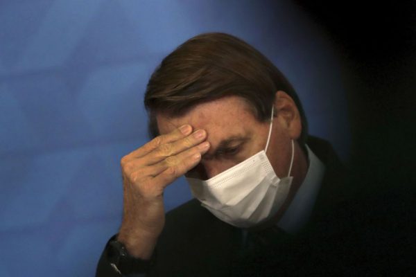 Brazil's President Jair Bolsonaro, wearing protective face mask, listens during a ceremony announcing economic measures to support philanthropic hospitals and help them treat COVID-19 patients, at the Planalto Presidential Palace, in Brasilia, Brazil, Thursday, March 25, 2021. (AP Photo/Eraldo Peres)